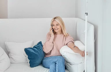 Blonde woman in pink sweater on sofa