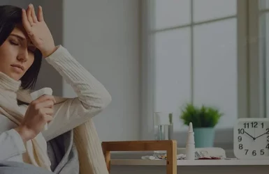 Sick woman on couch with thermometer