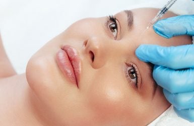 A person receives a forehead injection in a clinical spa