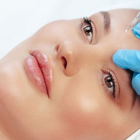 A person receives a forehead injection in a clinical spa