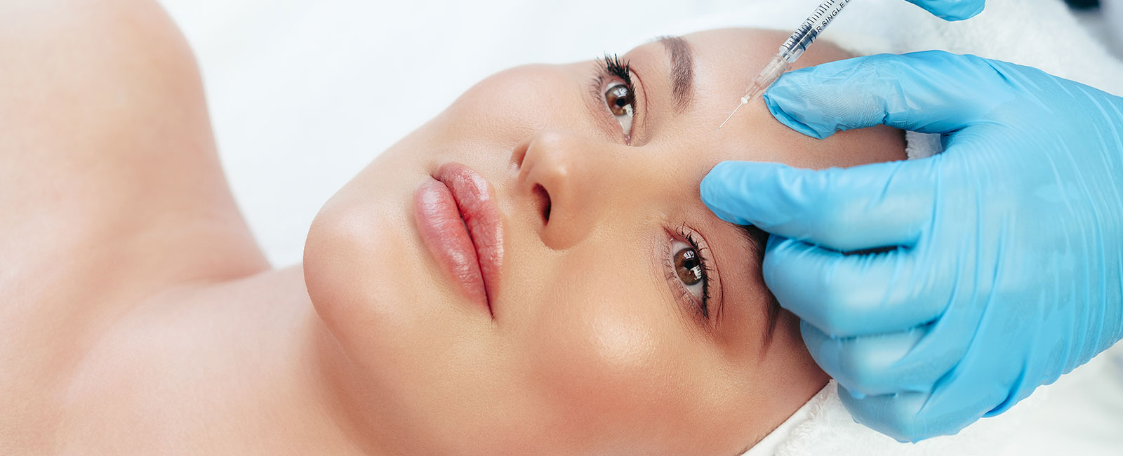 A person receives a forehead injection in a clinical spa