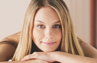 Blonde woman with blue eyes smiles gently