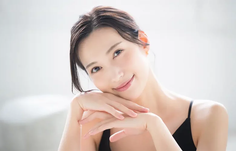 Dark-haired person in black top rests chin on hands; serene