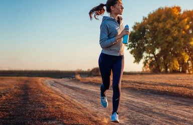Woman jogging on dirt path at sunset