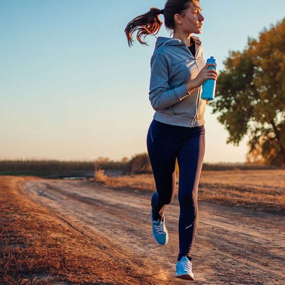 Woman jogging on dirt path at sunset