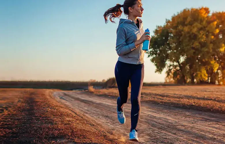 Woman jogging on dirt path at sunset