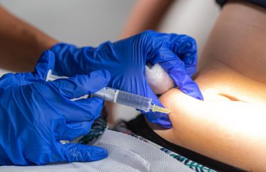 A healthcare professional injects lipolysis into the abdomen in a clinical setting.