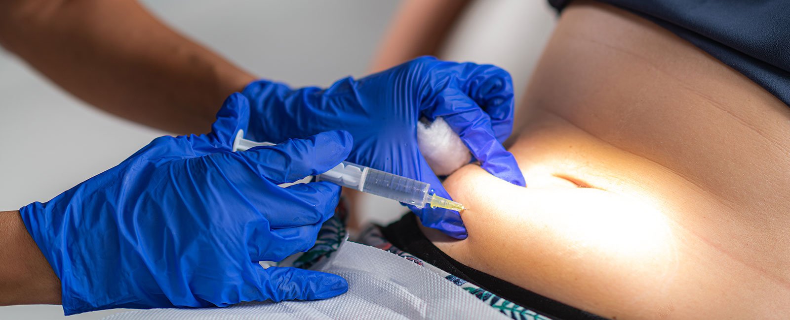 A healthcare professional injects lipolysis into the abdomen in a clinical setting.