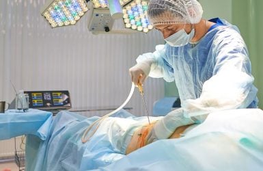 Surgeon performs liposuction on patient under bright lights