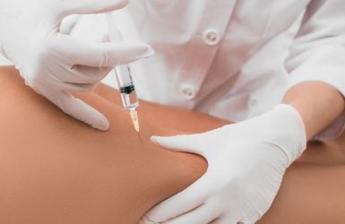 A healthcare professional gives a mesotherapy injection to a patient's thigh in a clinical setting.
