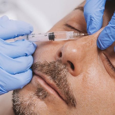 A professional injects a substance into a relaxed person's face during a non-surgical facelift.