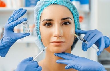 A calm woman in a blue cap is surrounded by syringes