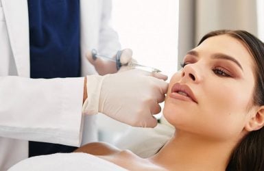A professional gives a facial injection to a relaxed woman in a treatment room.