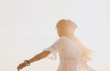 A woman in a white dress stands outside