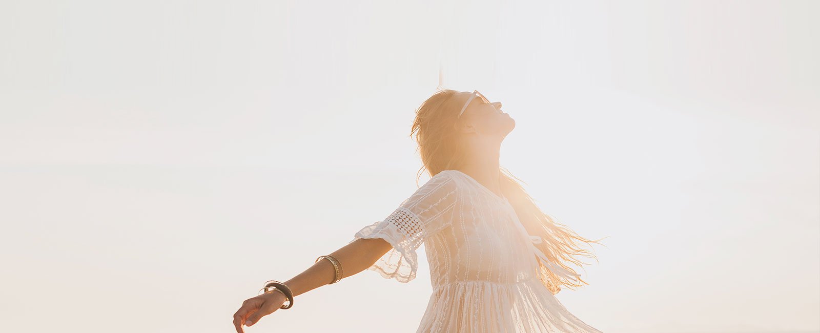 A woman in a white dress stands outside
