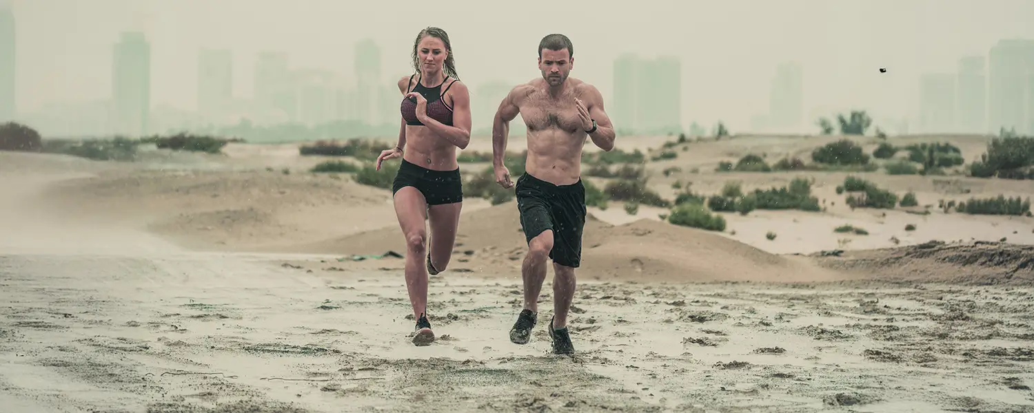 plastic-surgery-hawaii-hero-1 Two people run on a wet beach with a city skyline; overcast sky